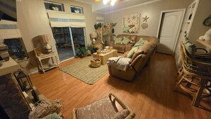 A cozy living room with a sofa, a coffee table, and a wicker chair. - Peaceful 3-bedroom house with AC in Flagler Beach (Flagler Beach)
