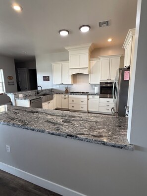 A modern kitchen with white cabinets, granite countertops, and built-in appliances.