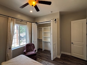 A bedroom with a bed, a chair, a closet, and a window with curtains.