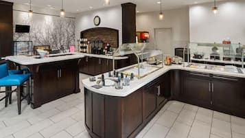 A modern kitchen with a central island, bar stools, and a built-in refrigerator.