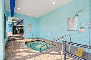 Ein kleiner Innenpool mit blauer Wand, einem Warnschild und einem Hinweisschild zu den Poolregeln.