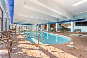 Ein Innenpool mit Ziegelboden, Liegestühlen und blauer Decke.