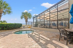 A pool area with a lifeguard sign, a covered outdoor seating area, and a view of the ocean. - Compass Cove Resort 462 (Myrtle Beach)