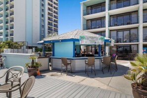 A small outdoor bar with a blue and white color scheme, a counter, and several chairs.