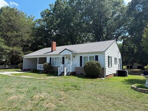 A single-story house with a porch, a chimney, and a small front yard.
