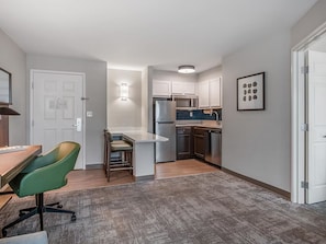 A compact kitchen with modern appliances, a dining area with a table and chairs, and a small office space.
