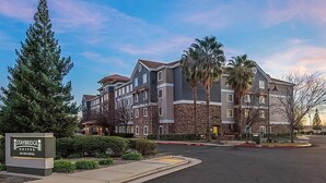 A multi-story hotel with a stone facade, a sign indicating it's a Staybridge Suites, and a parking lot in front. - Rocklin Suite with Kitchen | Free Daily Breakfast (Rocklin)