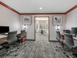 A conference room with two desks, chairs, and a carpeted floor.