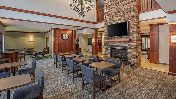 A spacious lobby with multiple seating areas, a fireplace, a television, and a clock on the wall. - Rocklin King Suite | Pool + Free Daily Breakfast (Rocklin)