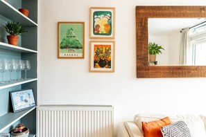 A living room with a radiator, a mirror, and three framed artworks on the wall. - Stylish Clapham Retreat Near the Common (London)