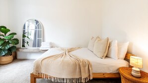 Una camera da letto con un letto, una lampada da comodino, una finestra vista e una pianta in vaso.