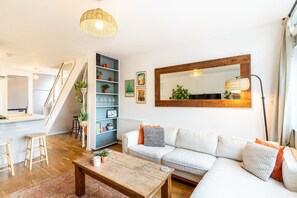 A modern living room with a sofa, coffee table, and shelves with plants. - Stylish Clapham Retreat Near the Common (London)