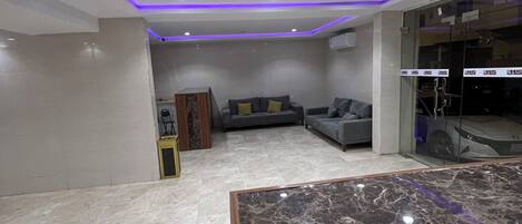 A spacious room with a marble floor, a sofa, and a glass partition.