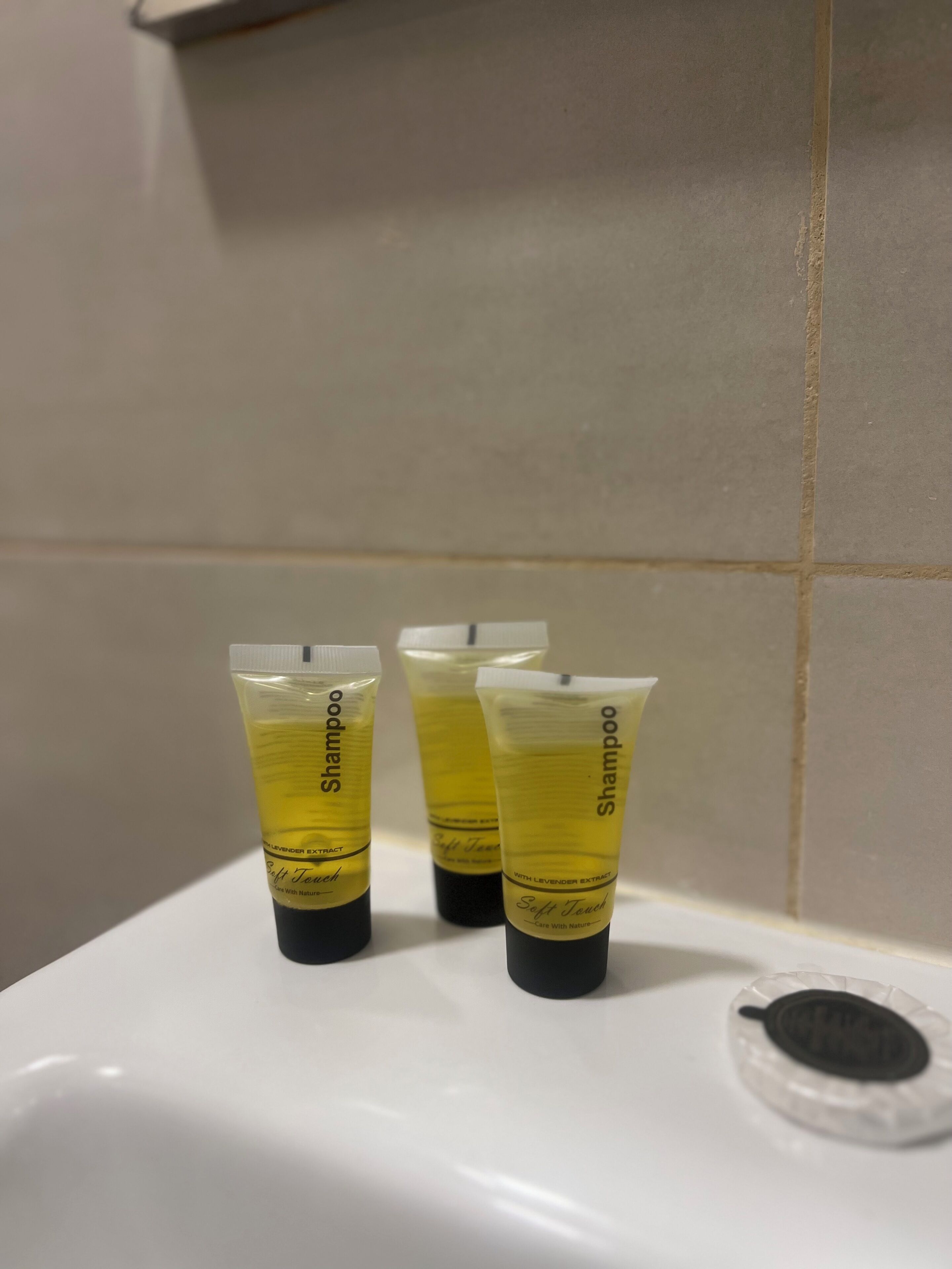 Three tubes of shampoo on a white sink.