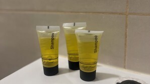 Três frascos de shampoo sobre uma pia branca.