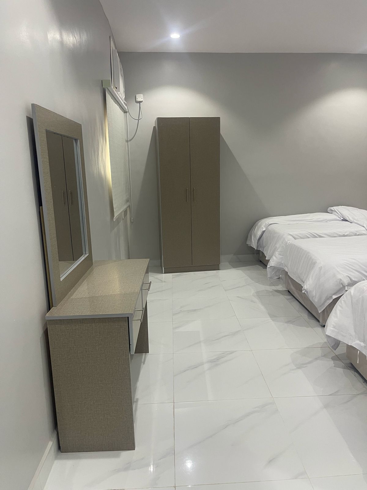Ein Schlafzimmer mit Bett, Kleiderschrank, Spiegel und Schreibtisch.