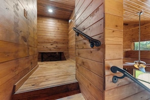 Un interior de madera con un banco, un ventilador de techo y una ventana.