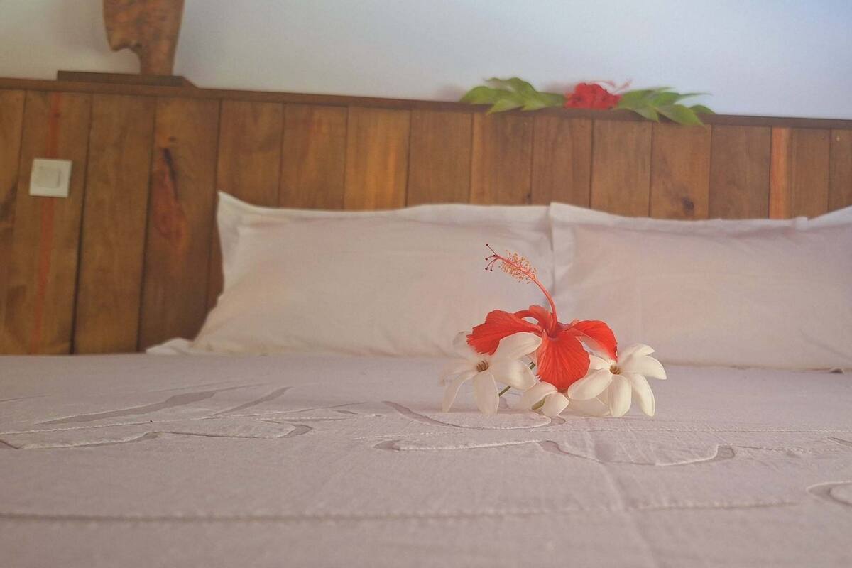 Una cama con sábanas blancas y un arreglo floral decorativo.
