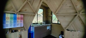 A small kitchen with a window, wooden beams, and a bulletin board with diagrams. - Glamping Cabin in a Private Forest, 15 Minutes from José María Córdova Airport (Rionegro)
