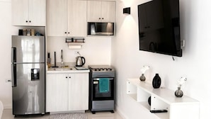 Een moderne keuken met witte kastjes, een roestvrijstalen koelkast, een magnetron en een inbouwoven.