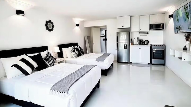 Een moderne hotelkamer met twee bedden, een kitchenette en een eethoek.