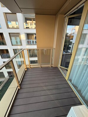 Parveke, jolta on näkymä naapuritaloihin, lasiovi ja metallikaide.