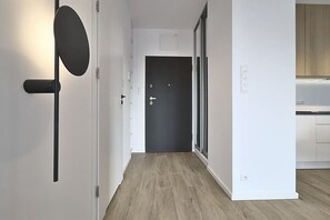 Käytävä, jossa on ovi, valaisin ja keittiöalue.