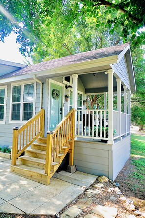 A house with a covered porch, a wooden staircase, and a front door with a wreath. - Cozy 1 bedroom 1 bath with loft  tiny home 2 pools & hot tub Lake Travis (Austin)
