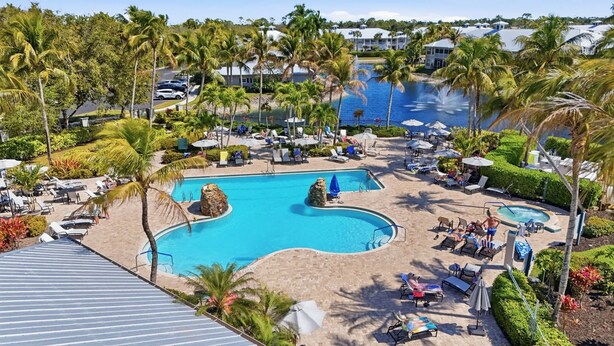 Ett semesterhotell med en central pool, solstolar, palmer och utsikt över havet.
