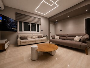 Een moderne woonkamer met twee banken, een salontafel en een flatscreen televisie aan de muur.