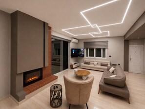 Ein modernes Wohnzimmer mit Kamin, Flachbildfernseher, Sofa und Couchtisch.