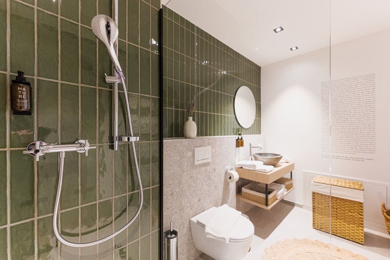 Een moderne badkamer met een douche, toilet, wastafel en spiegel.