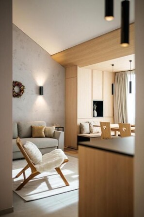 A modern living room with a sofa, a chair, and a dining area with a table and chairs. - Lebe' Oetz im Ötztal  (Oetz)