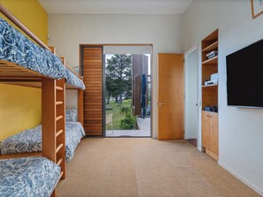 Ein Zimmer mit Etagenbetten, einer Holztür, Teppichboden und einem Bücherregal.
