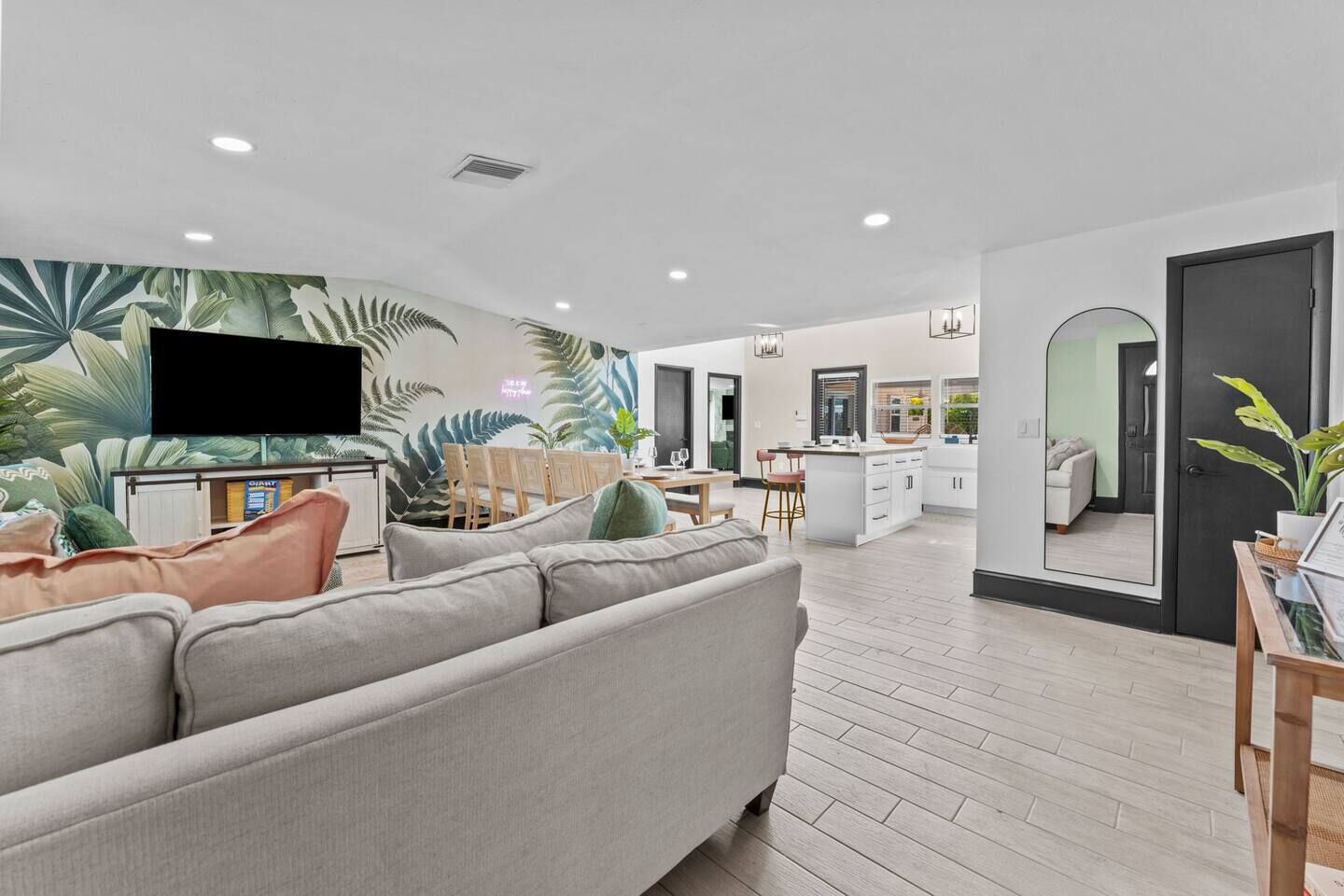 A modern living room with a sofa, a TV, and a kitchen in the background.