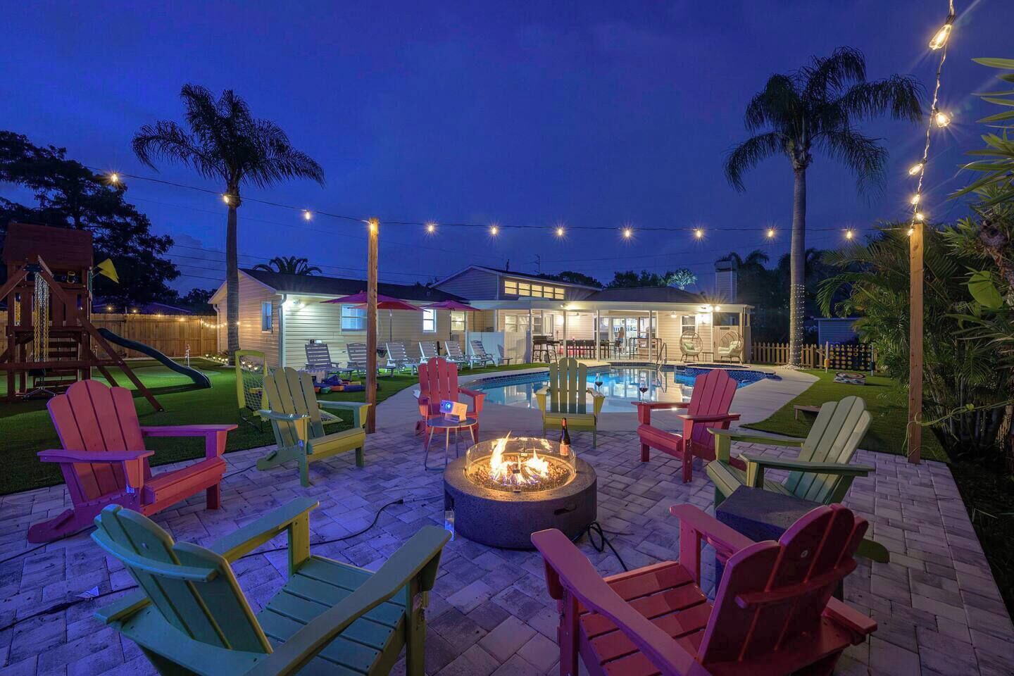 A backyard with a swimming pool, outdoor seating, and a fire pit.
