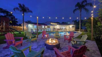 A backyard with a swimming pool, outdoor seating, and a fire pit.
