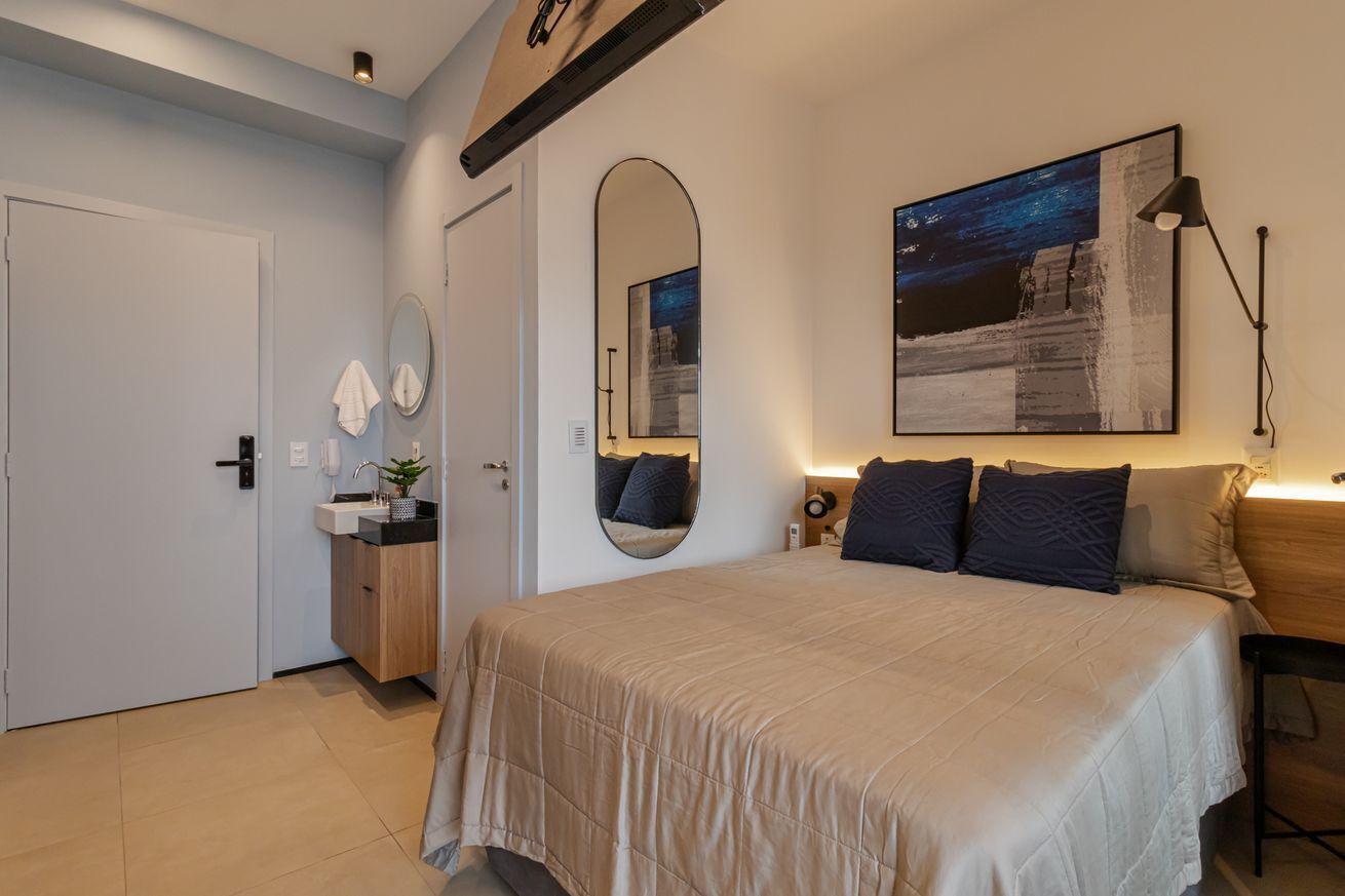 Una camera da letto con un letto grande, un comodino, uno specchio, un quadro e una lampada.