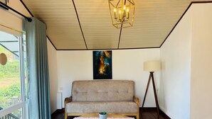 Et værelse med en sofa, et bord med en plante, en lampe og et billede på væggen.