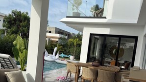 Zona exterior moderna amb piscina, gandules i taula de dinar.