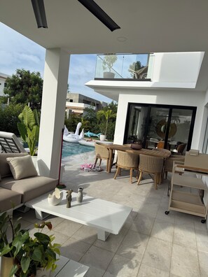 A modern outdoor living area with a pool, lounge chairs, and a dining table. - Spacious 5-bedroom house in beautiful Punta Cana with AC (Punta Cana)
