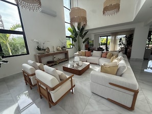A spacious living room with a sectional sofa, a coffee table, and a console table with decorative items. - Spacious 5-bedroom house in beautiful Punta Cana with AC (Punta Cana)