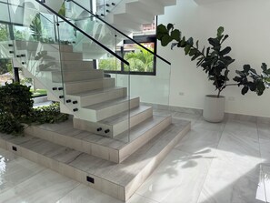 A modern staircase with glass railings and a potted plant. - Spacious 5-bedroom house in beautiful Punta Cana with AC (Punta Cana)