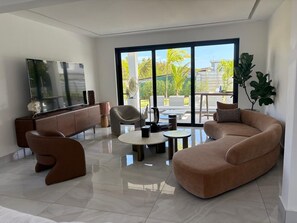 A modern living room with a sofa, armchairs, a coffee table, and a TV. - Spacious 5-bedroom house in beautiful Punta Cana with AC (Punta Cana)