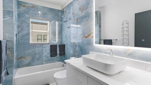 Een moderne badkamer met een badkuip, toilet en een grote spiegel boven de wastafel.