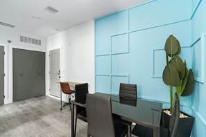 A modern conference room with a glass table, black chairs, a brown chair, a blue accent wall, and a potted plant. - Hyde Park 1/1 private residence 3 (Tampa)