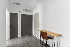 A hallway with a desk and chair, a white door, and a vent on the ceiling. - Hyde Park 1/1 private residence 3 (Tampa)