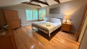 Un dormitorio con cama, mesitas de noche, un radiador y suelo de madera.