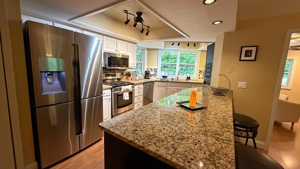 Una cocina moderna con electrodomésticos de acero inoxidable, encimeras de granito y un amplio ventanal que proporciona luz natural.