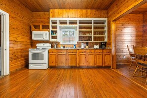 Una cocina con armarios de madera, microondas, estufa y ventana.